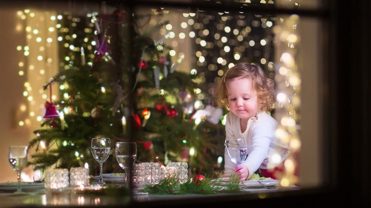 Image of a small child surrounded by Christmas lights reaching for a drink on a table decorated with candles and glassware - two bedroom handicap apartments in lafayette la 